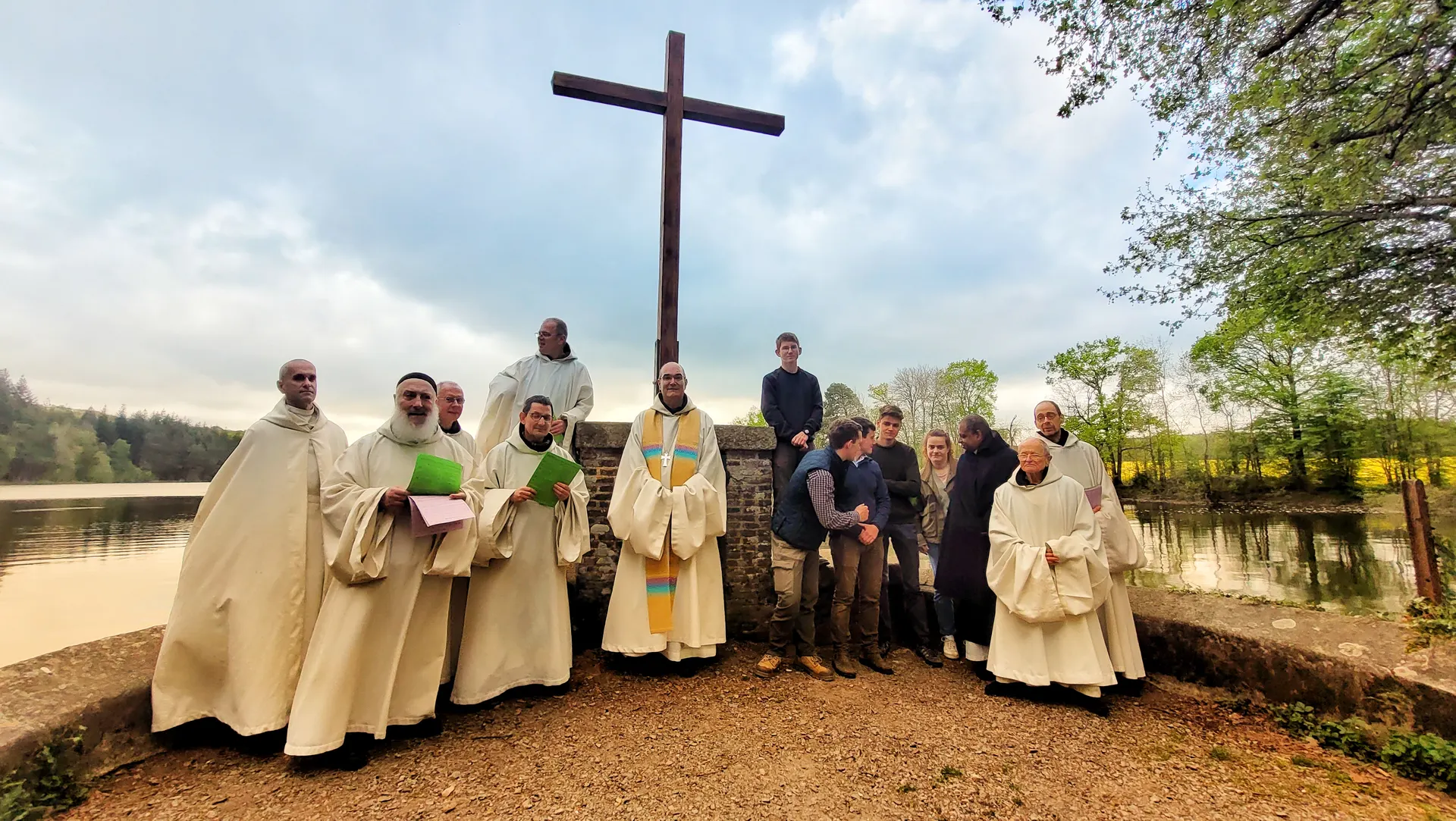 Les frères et des jeunes rassemblés autour d’une grande croix de bois, au bord de l’eau