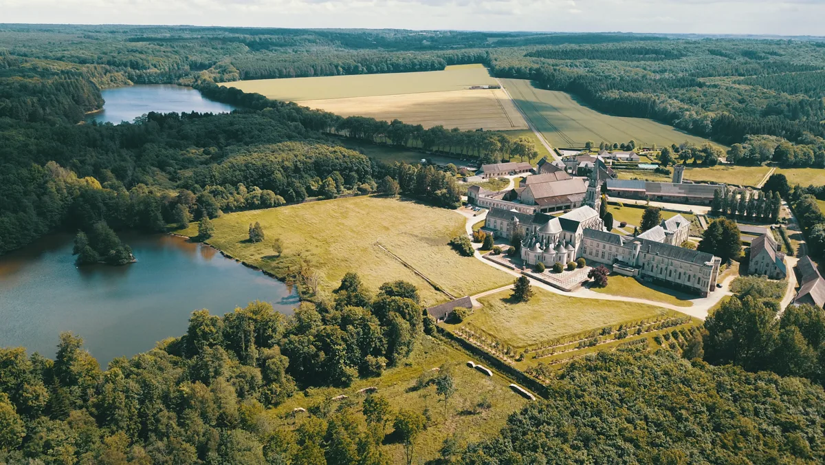 L’abbaye, ses toits et ses étangs vus du ciel, au milieu des bois
